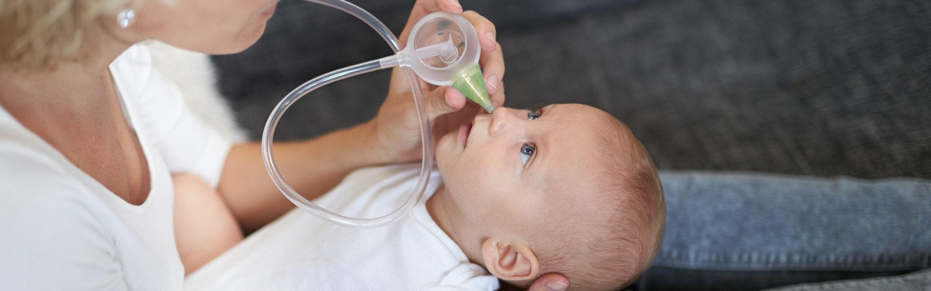 A woman clearing the nose of her smiling son with the help of the Nosiboo Eco Manual Nasal Aspirator