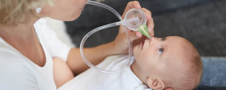 A woman clearing the nose of her smiling son with the help of the Nosiboo Eco Manual Nasal Aspirator