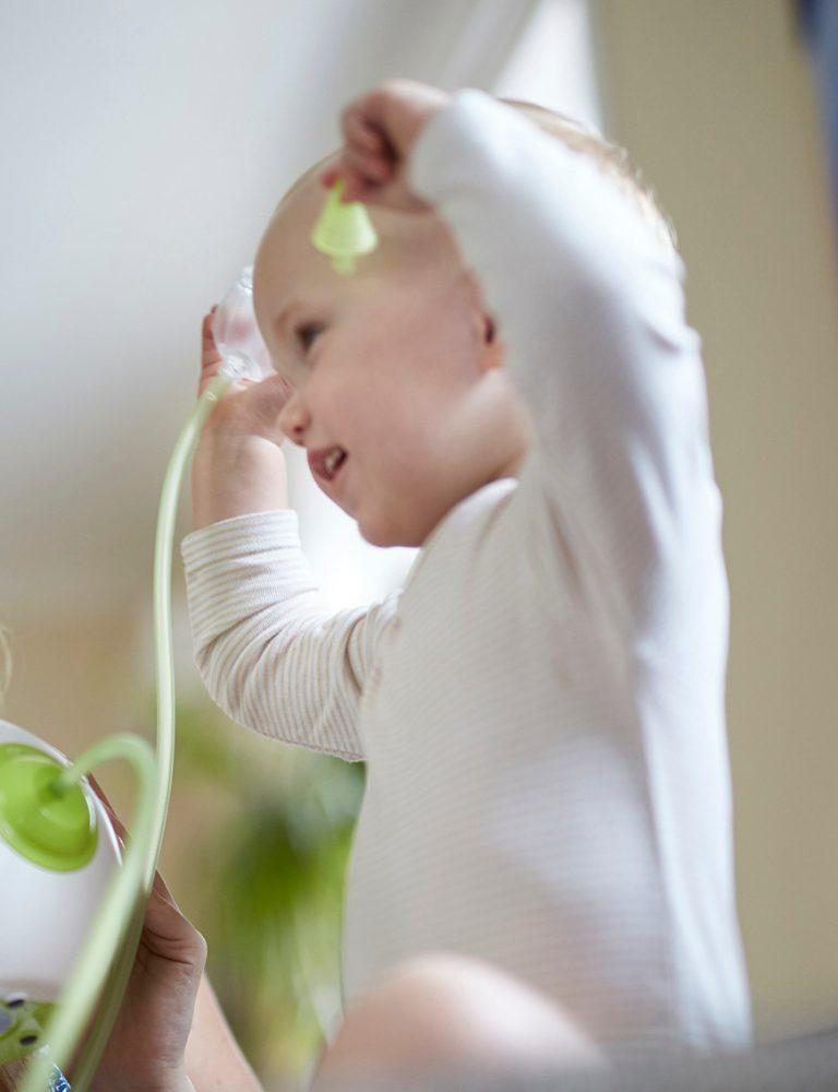 A woman clearing her son's nose with the help of the Nosiboo Pro Electric Nasal Aspirator