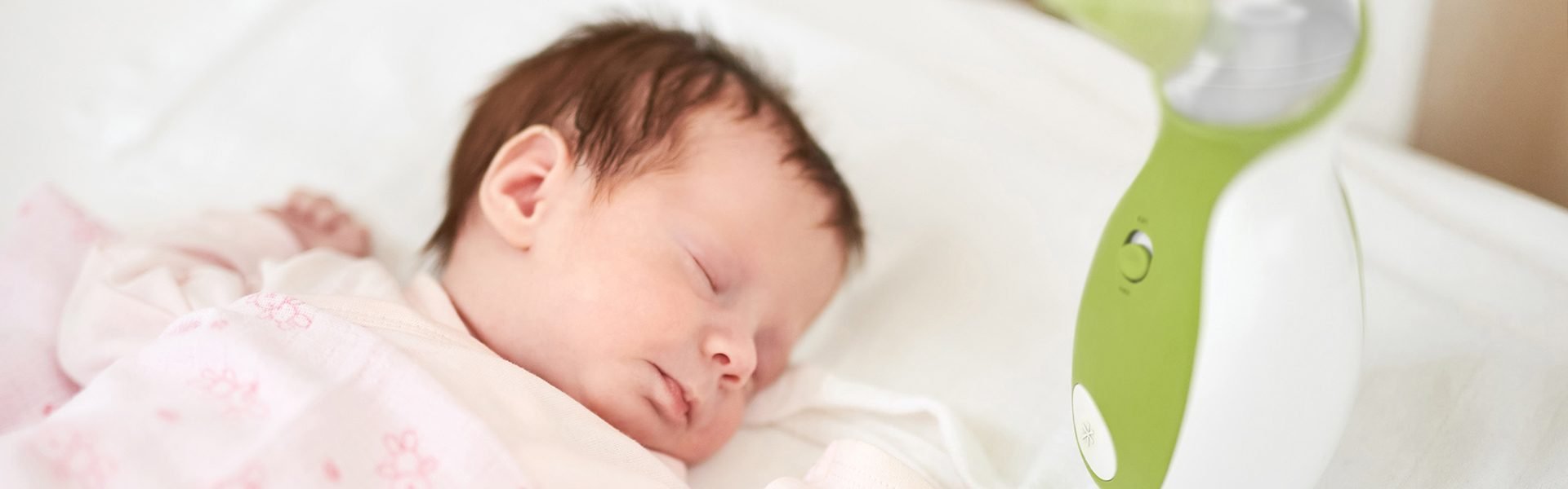 A baby boy sleeping peacefully in his bed next to the Nosiboo Go Portable Nasal Aspirator