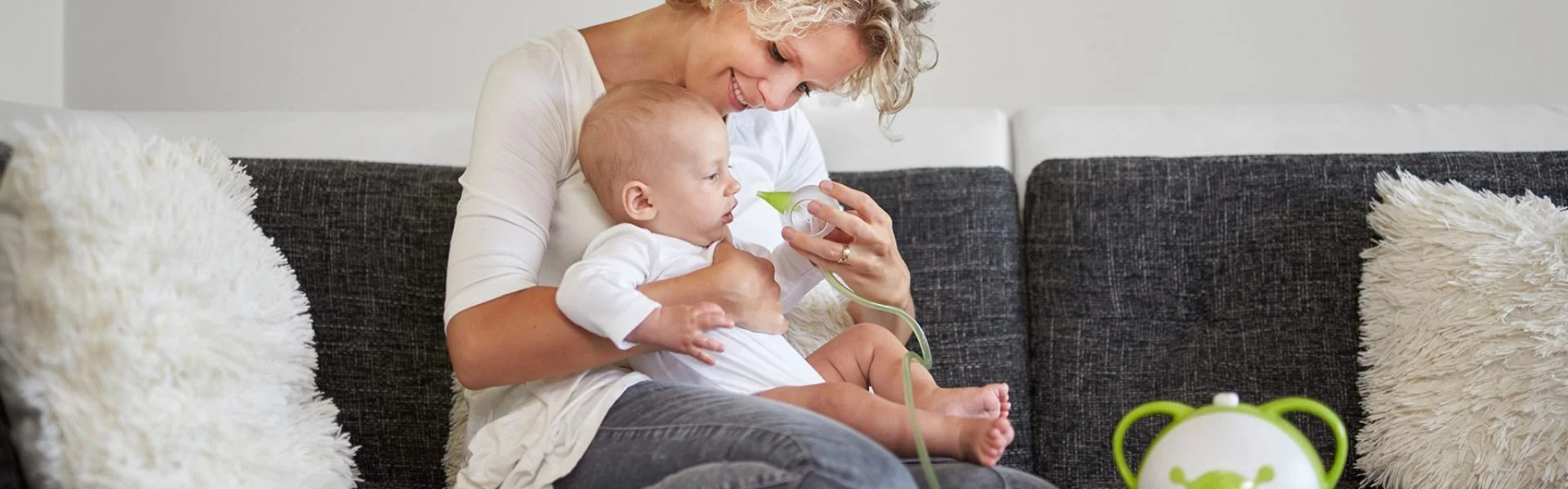 A woman clearing a boy's nose with the help of a baby nasal aspirator Nosiboo Pro