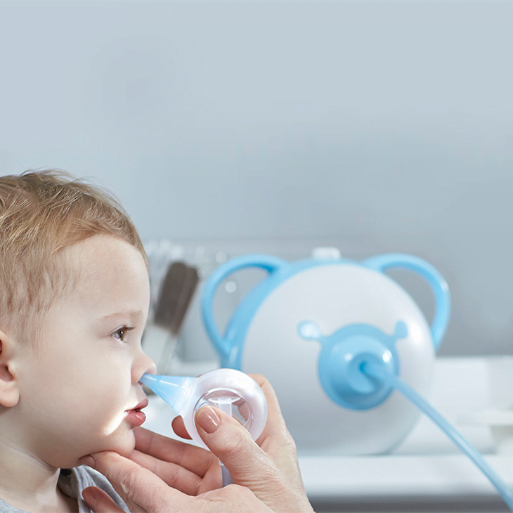 An ENT doctor clearing a boy's nose with the help of a safe baby nasal aspirator Nosiboo Pro