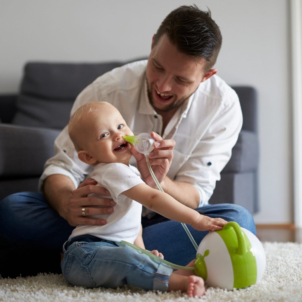 A father clearing his son's nose with the help of the Nosiboo Pro Electric Nasal Aspirator