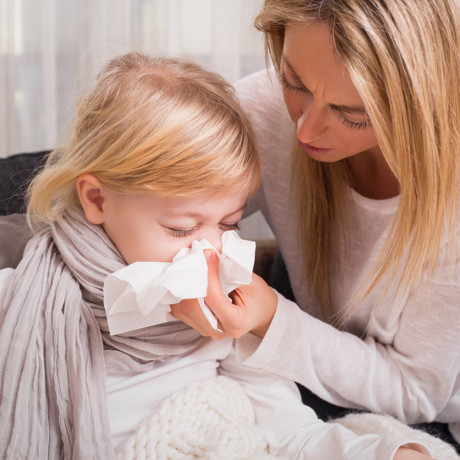 A little girl blowing her nose into a tissue